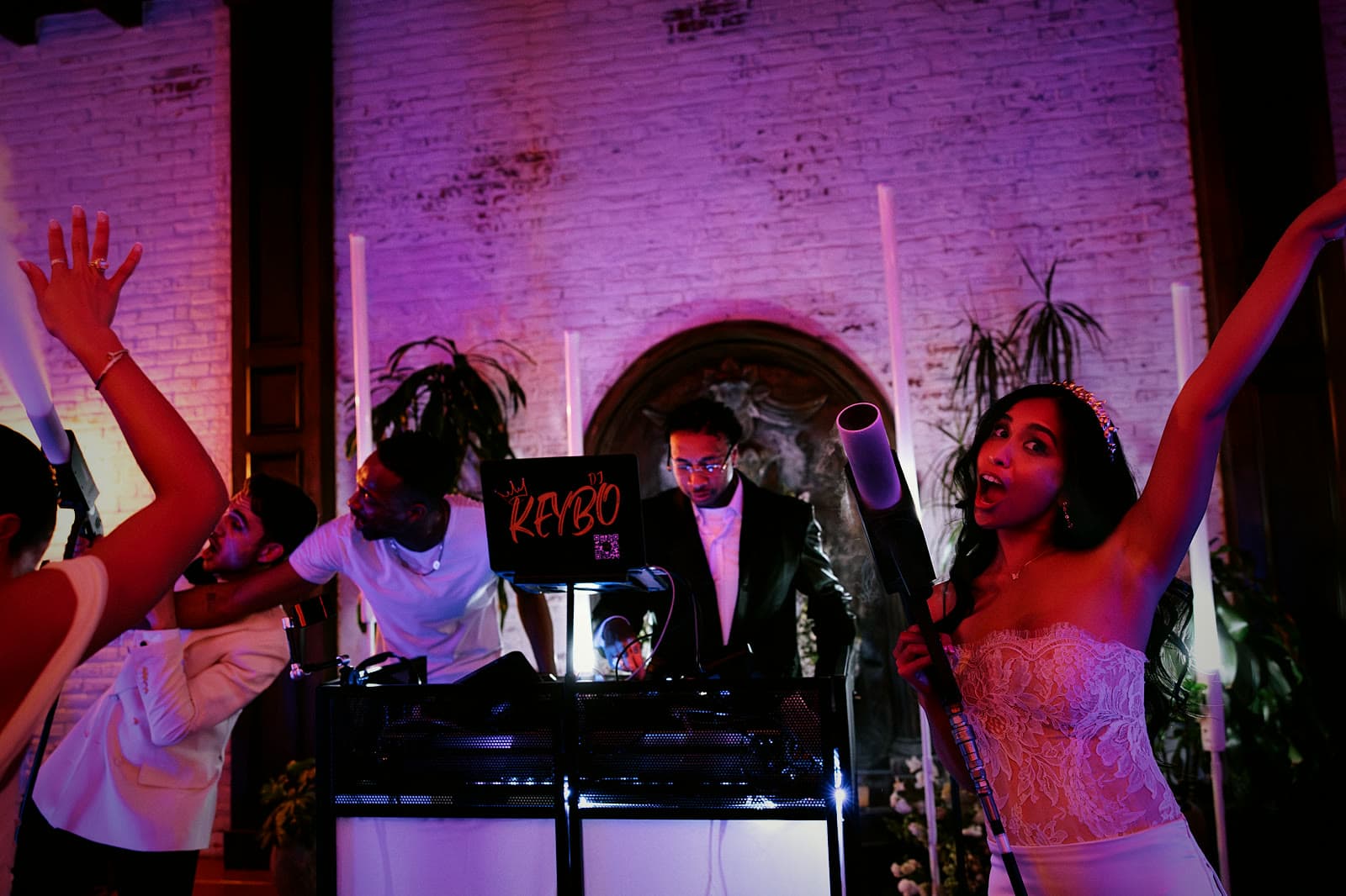 Bride with her arms up beside DJ Keybo's booth