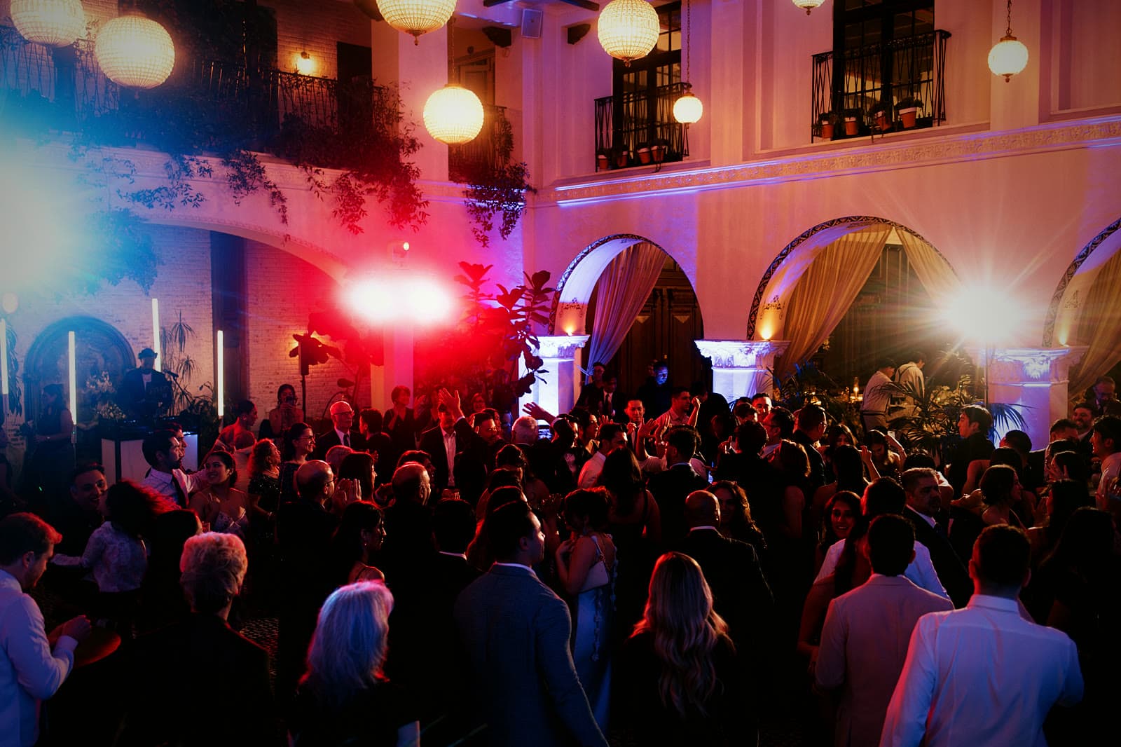 Packed courtyard reception under lanterns and uplighting